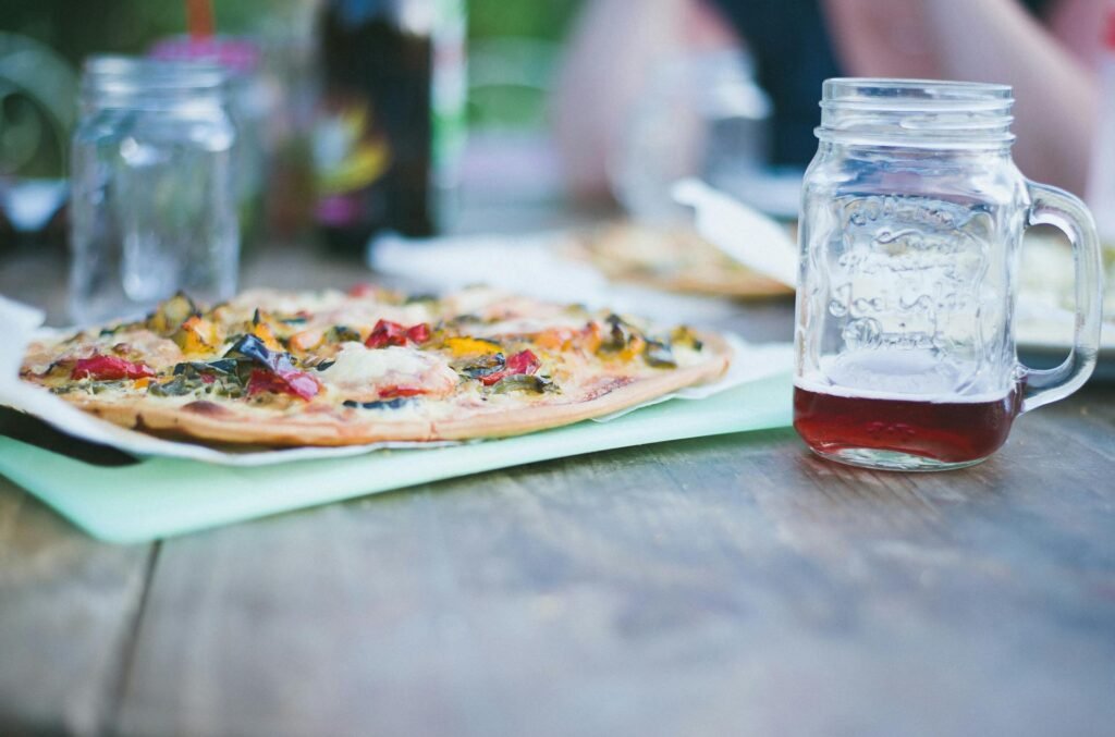 pexels-photo-238306-238306 A rustic outdoor setting featuring a delicious homemade pizza with vibrant toppings and a refreshing beverage in a rustic mason jar.